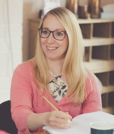 Michaela wearing a pink top and writing