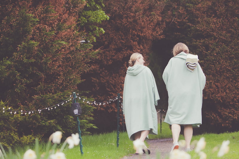 two women walking away from a spa in robes